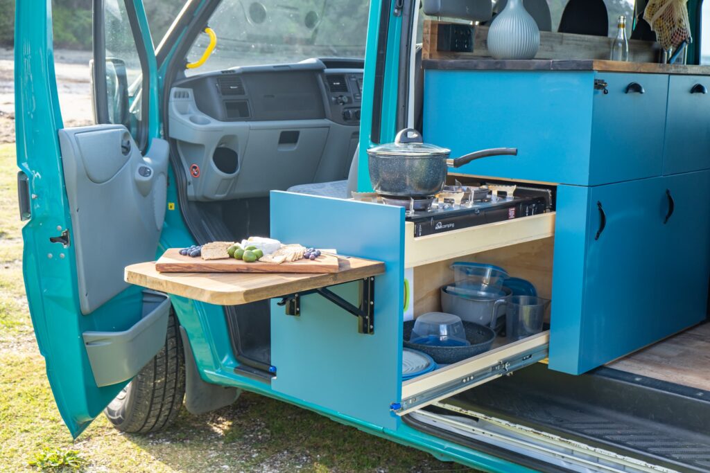 Exterior view of a quirky campers campervan conversion with outside cooker and pop-out table.