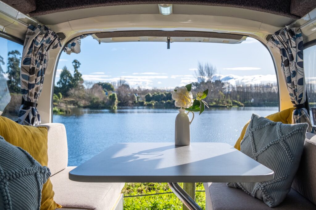 A view to a picturesque lake through the back door of a completed campervan conversion
