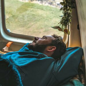 Man relaxing looking out of the window from the back of his campervan