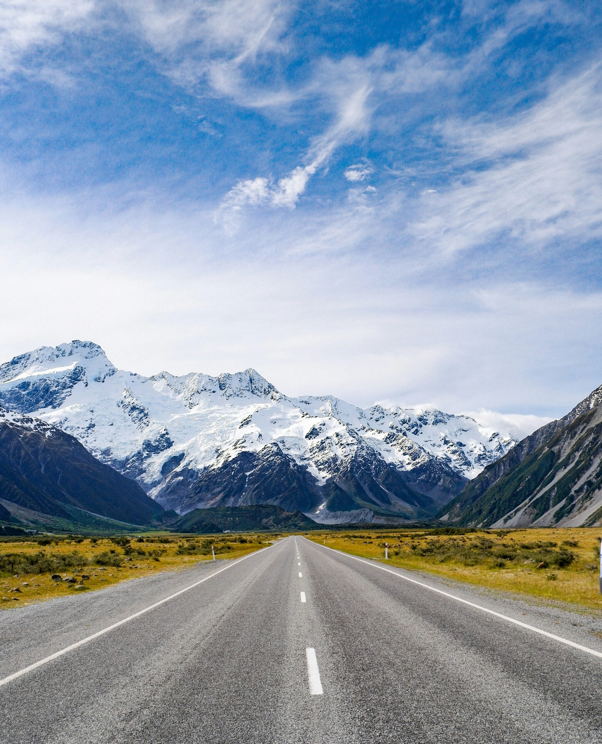 A dramatic open road stretching towards the New Zealand mountains