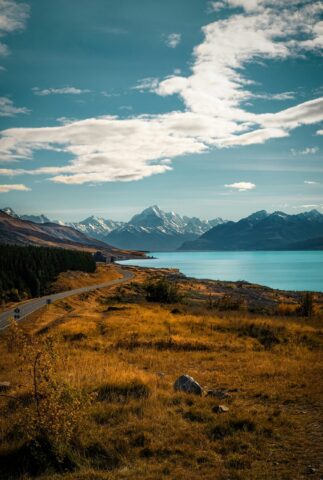 A campervan on an open road winding through New Zealand mountains