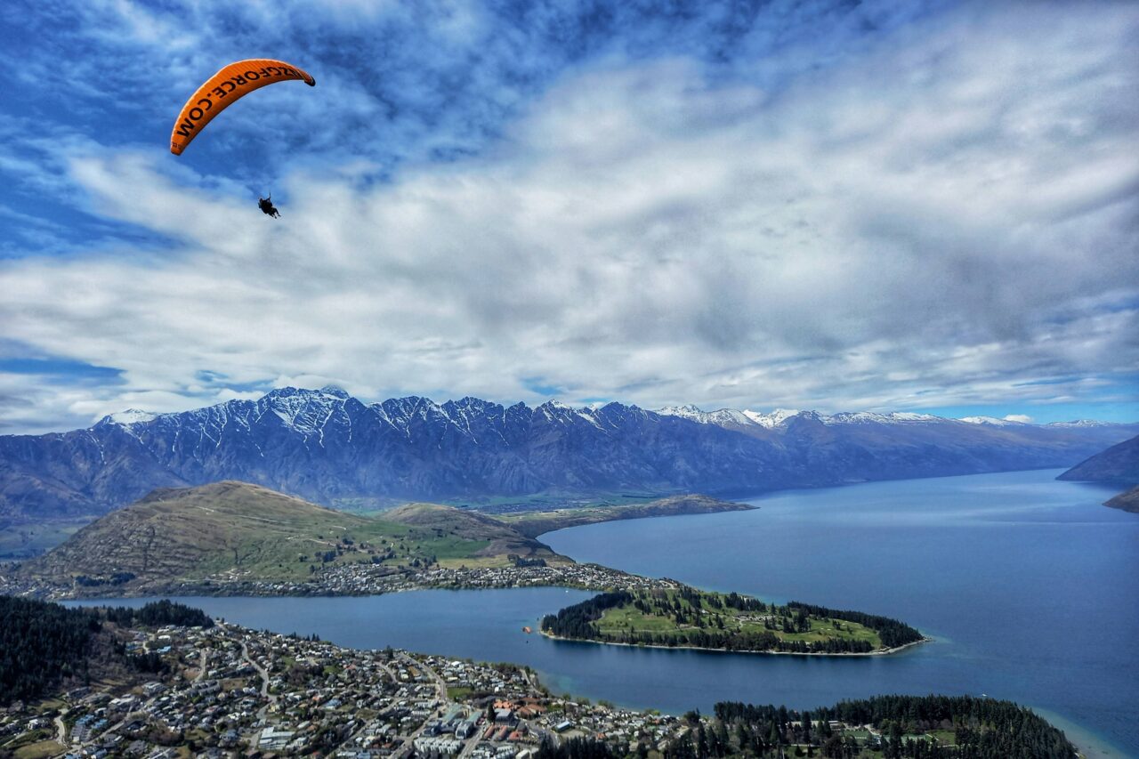 A paraglider drifting above Queenstown with Lake Wakatipu below