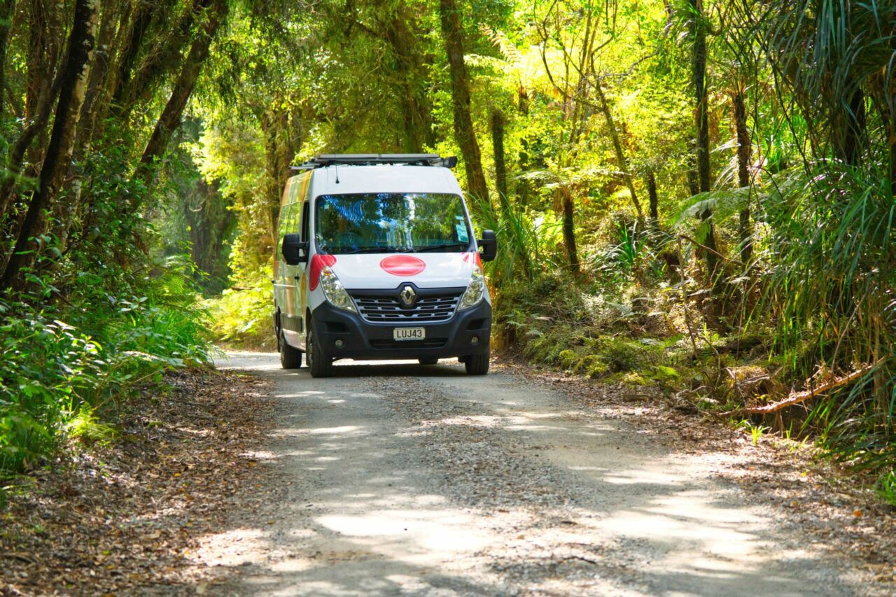 Quirky campervan Berry driving through West Coast rainforest near Hokitika
