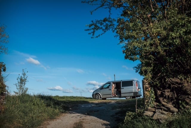 A Mercedes campervan parked at the end of the road on route to a festival