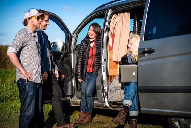 Four people hanging out at their campervan with their laptop