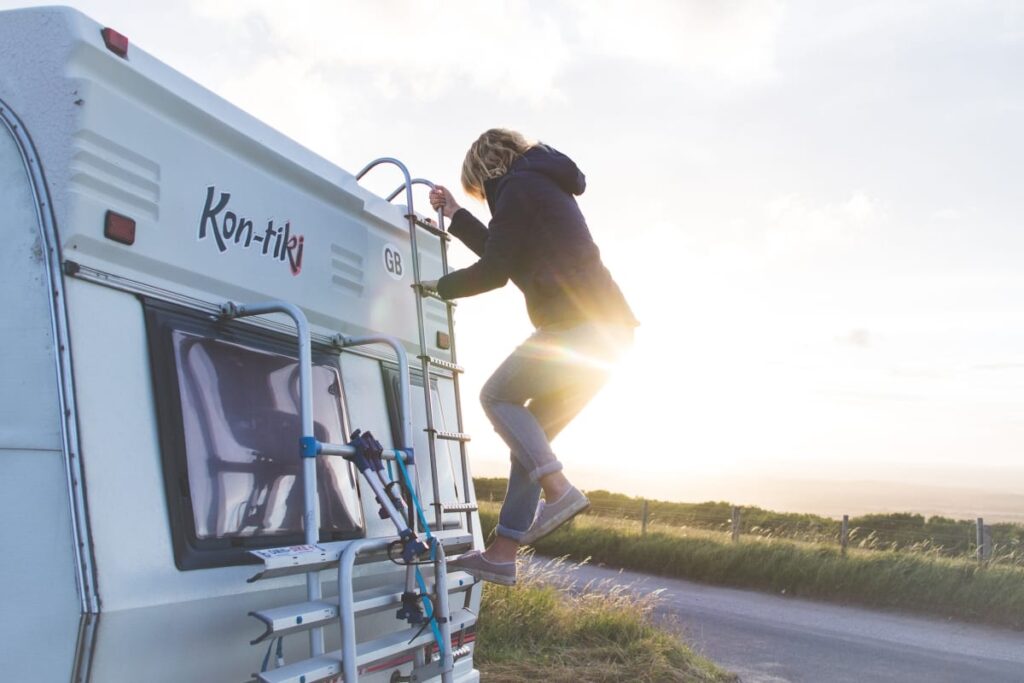 A woman climbing down the ladder on the back of Tiki, Quirky Campers' retro campervan.