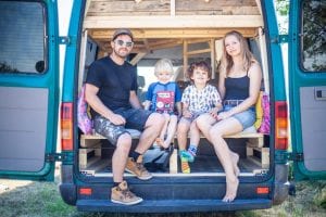 Family with two young children sit in the back of their self-built quirky campervan