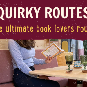 A woman is sitting on a pink couch reading a book with a yellow cover at a wooden table. The table has two green glass goblets, a bottle of wine, and a second book. Above, the text reads "QUIRKY ROUTES: The ultimate book lovers route" in bold white and yellow letters on a burgundy background.