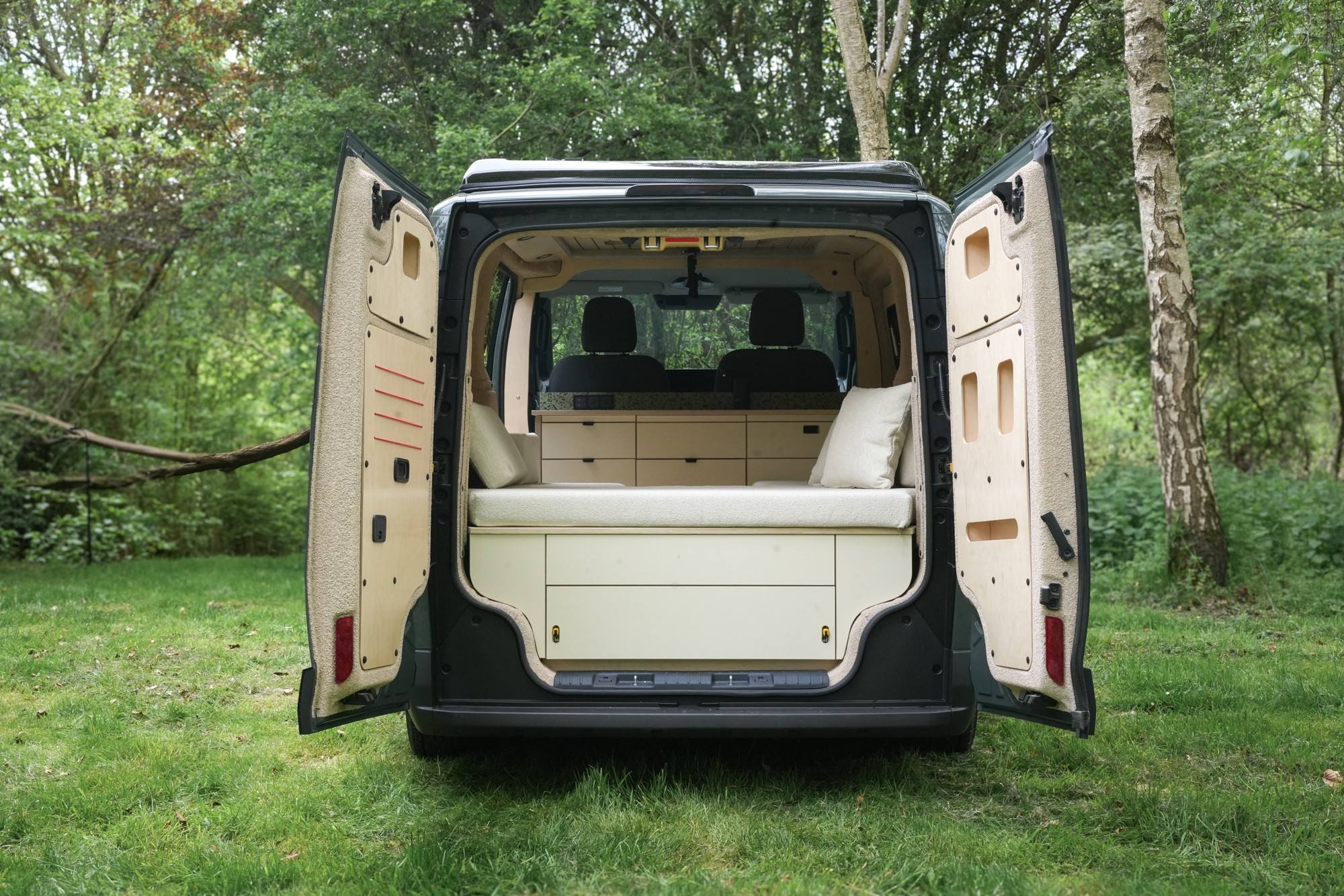 Campervan with both rear doors open showing a view of the neutrally coloured interior