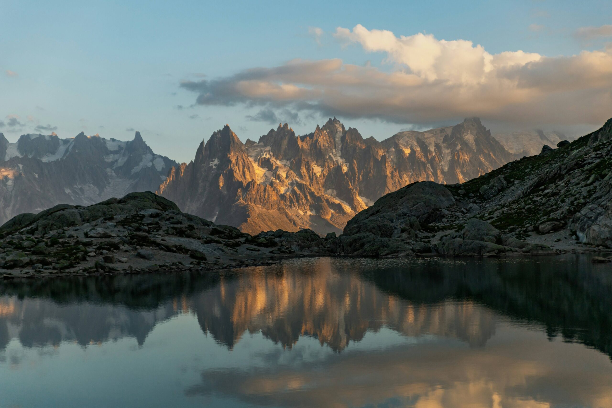 Majestic mountains of Chamonix silhouetted against a vibrant sunset, mirrored in the calm waters of a lake.