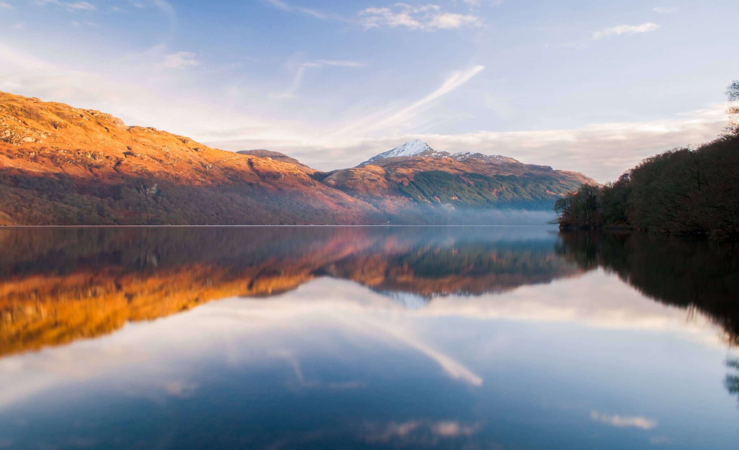 A picturesque mountain range reflects perfectly in a still lake, highlighting the harmony between land and water.