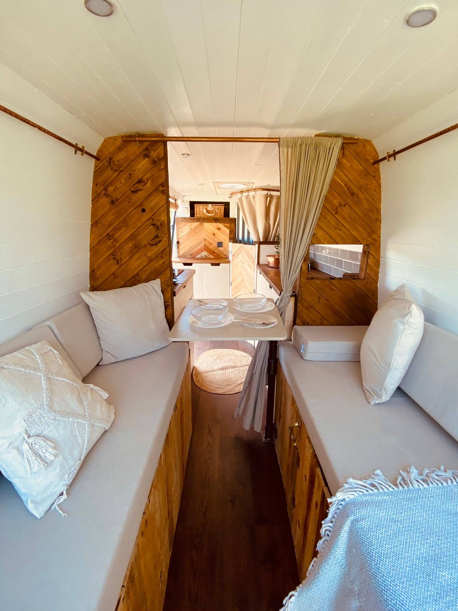 Interior of a camper van featuring a cozy bed and a comfortable seating area, designed for relaxation and travel.