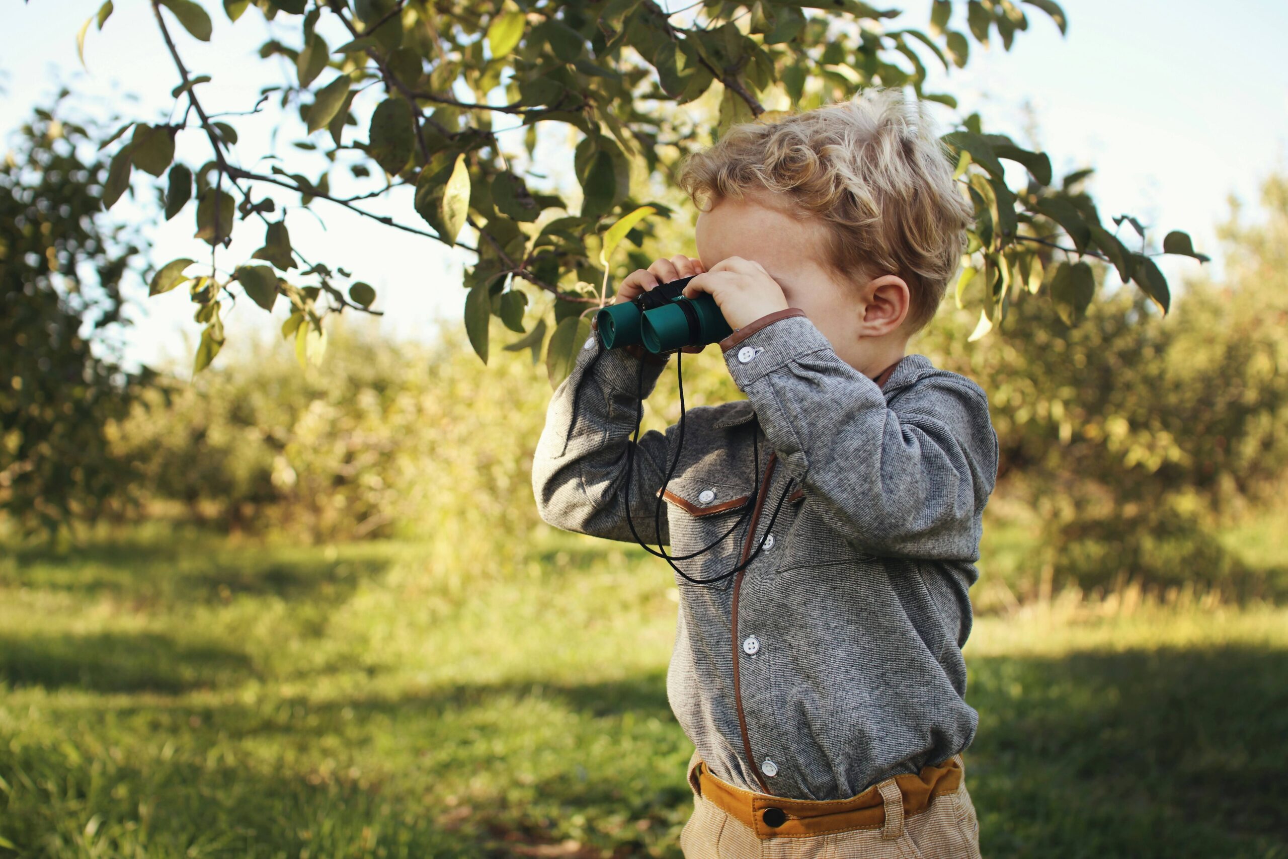 Young child outdoors looking through binoculars