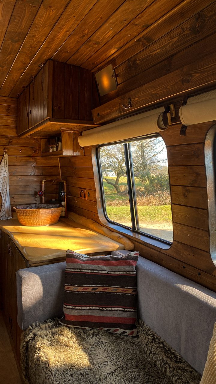 A cosy sofa inside a campervan, showcasing a warm, compact and inviting living space.