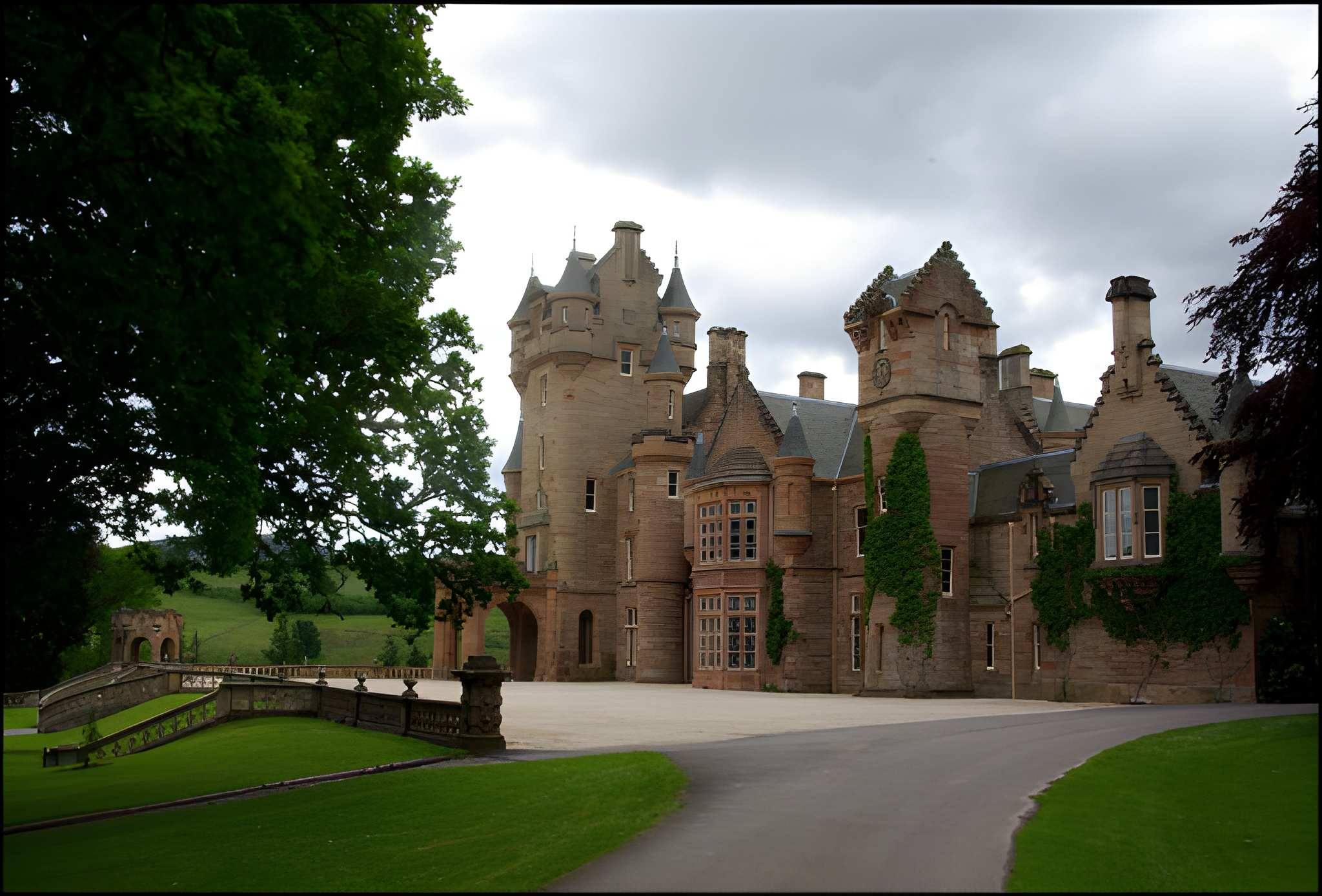A historic stone castle with towers and ivy stands beside a curved driveway, framed by lawns and trees beneath a cloudy sky; the scene feels quiet and stately.